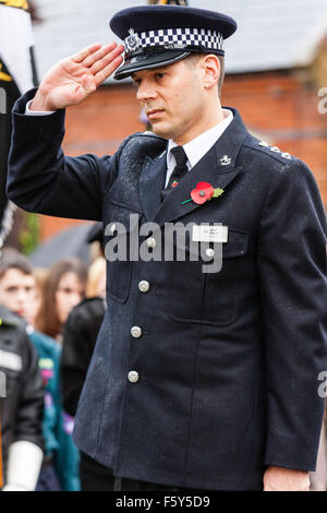 England, Ramsgate. Remembrance Day. Senior police officer saluting at war memorial during ceremony in the rain. Wears poppy in lapel. Stock Photo