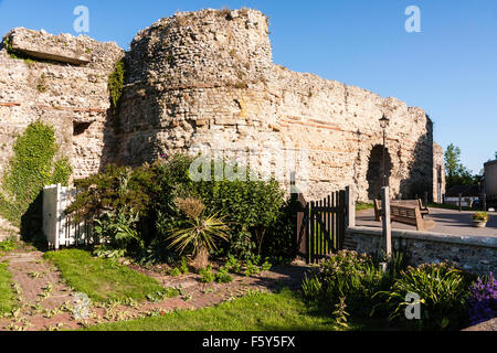 England. Roman 4th century Saxon Shore fort, Pevensey castle. East gateway with defensive tower and walls. Blue sky. Garden in foreground. Stock Photo