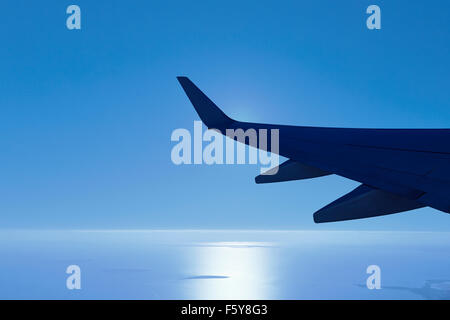Plane Boeing 737-800 wing with early morning sun glowing from behind the wing. Stock Photo
