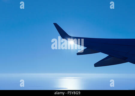 Plane Boeing 737-800 wing with early morning sun flaring from just behind the wing. Stock Photo