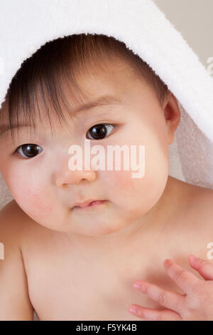 Cute Asian baby sitting with a towel over his head Stock Photo