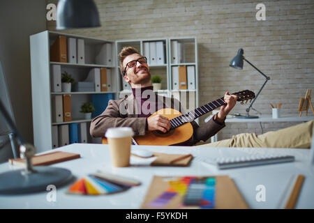 Cheerful businessman playing the guitar during business break Stock Photo