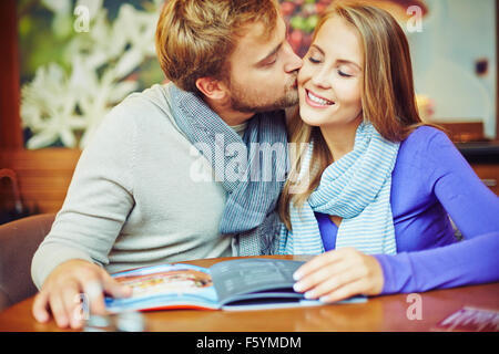 Happy young couple sitting in café and kissing Stock Photo
