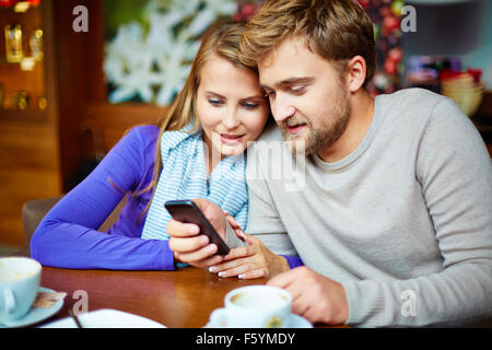 Young couple using mobile phone in cafe Stock Photo