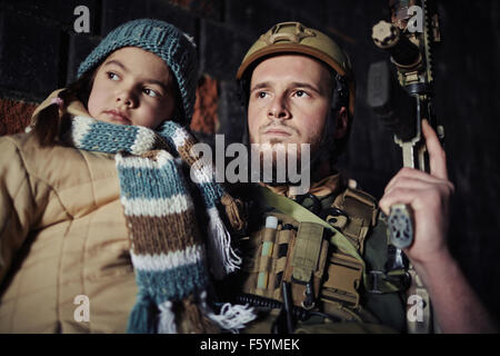 Military man in camouflage holding gun and little girl Stock Photo