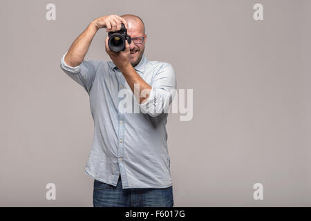 Male photographer focusing and composing an image with his professional digital Dslr camera pointing the lens directly at the vi Stock Photo