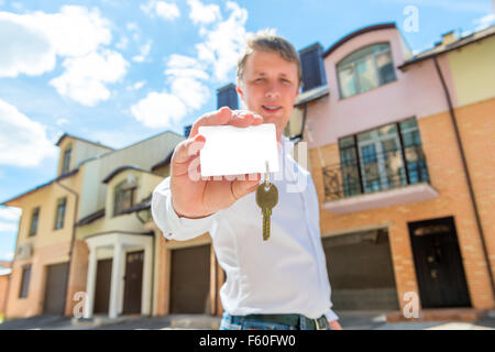 man stands near the house and shows the key to the apartment Stock Photo