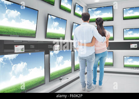 Composite image of attractive young couple standing with arms around Stock Photo