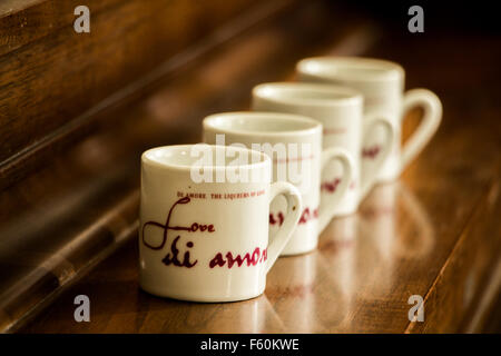 Four mugs lined up in a row on a wooden surface. Stock Photo