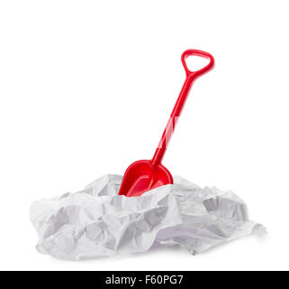 Red plastic toy shovel in crumpled paper isolated on a white background. Stock Photo