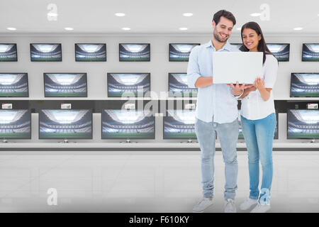 Composite image of attractive young couple holding their laptop Stock Photo