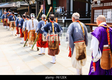 Japan, Nishinomiya, Mondo Yakuji temple. Possession of Priests wearing yamabushi, (Warrior monk), costumes, walking in line pass temple hall. Stock Photo