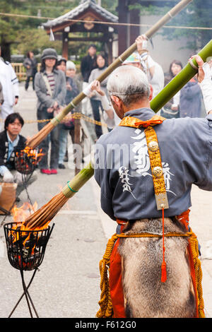 Japan, Nishinomiya, Mondo Yakuji, Shotaizan Tokoji temple. Priests in yamabushi costume lighting large bamboo torches during religious ceremony. Stock Photo