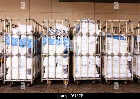 Japan, Kyoto. Row of four hotel laundry trollies, filled with white and some blue towels outside hotel awaiting collection. Stock Photo