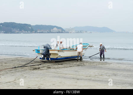 Fishermen hauling a boat of the sea at the beach in Kamakura, Japan. Stock Photo