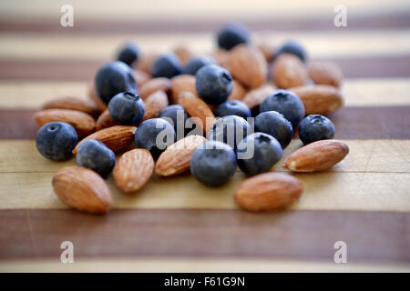 A bunch of almonds and Blueberries on a cutting board ready to become part of a healthy nutritious snack. Stock Photo
