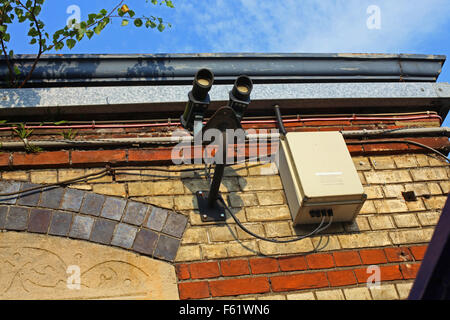 Two laser receivers and an associated connection box on the side of a building with an old cast iron gutter above them Stock Photo