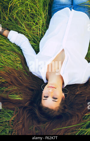 Beautiful Young Woman Relaxing Outdoors in Green Grass Stock Photo