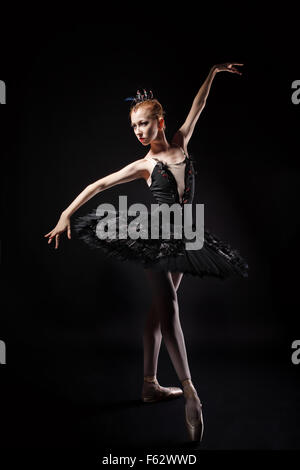 Slim ballerina in a black corset and black tutu. Rehearsal in the theater. Classical Ballet. Photography in low key. Stock Photo