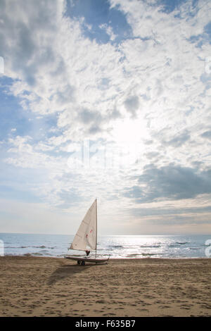 small sailboat on a cart at the beach ready to sailing. life jacket hanging from the boom. sun is shining between white clouds Stock Photo