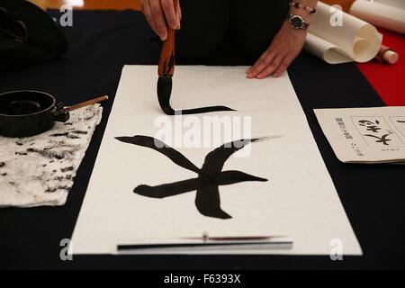 Araditional Japanese calligraphy artist creates a scroll during the Japanese Calligraphy Brush Festival September 23, 2015 in Kumano, Hiroshima Prefecture, Japan. Each autumn equinox artists gather in the mountain town where 80% of the traditional brushes are crafted. Stock Photo