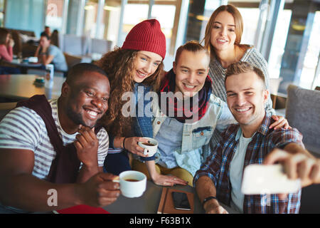 Friendly teenagers making selfie in cafe
