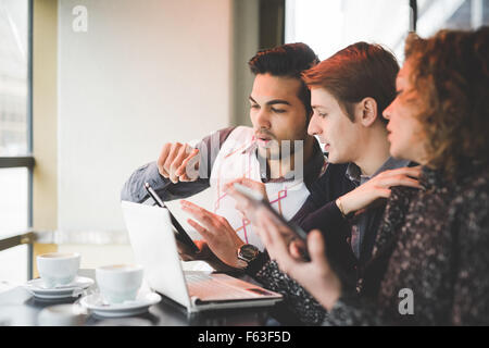 Group of multiracial business people working sitting in a bar having a coffee, connected with technological devices like smartphone, tablet and notebook - technology, working, business concept Stock Photo