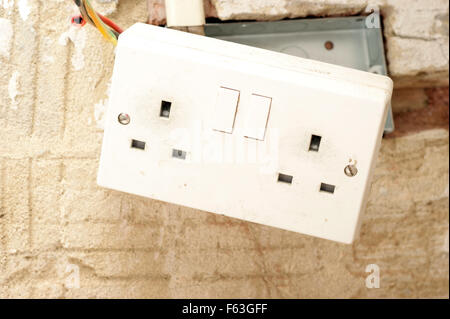 Electric plug sockets with exposed wiring in a rented social housing property house that needs attending to Stock Photo