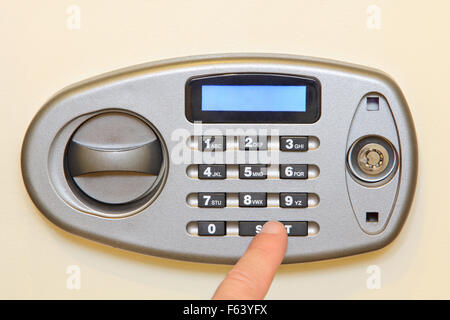 Man finger press start button on electronic home safe. Stock Photo