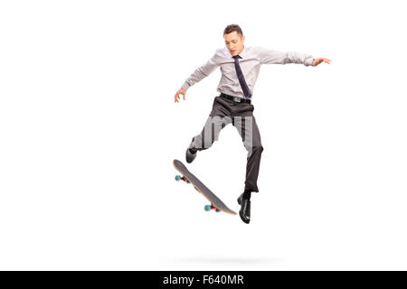 Studio shot of a young businessman performing a trick with a skateboard shot in mid-air isolated on white background Stock Photo