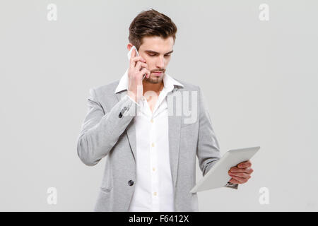 Young handsome businessman talking on cellphone and using tablet Stock Photo