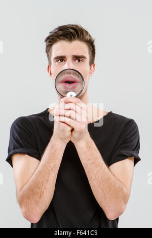 Handsome carismatic young freak man using magnifying glass Stock Photo
