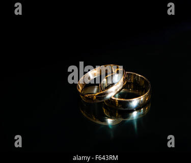 Two men's wedding bands on a reflective black background Stock Photo
