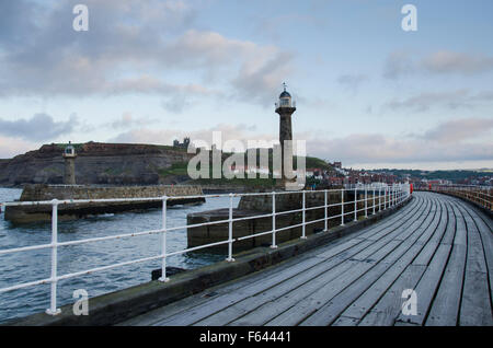 Evening view of 2 lighthouses, harbour entrance and curving West Pier, Whitby, North Yorkshire, GB - Abbey and St. Mary's Church on the cliffs beyond. Stock Photo