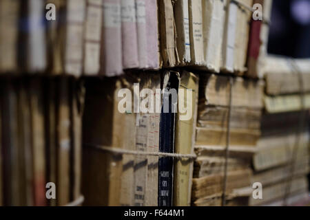 Stack of worn old books wrapped together on a shelf Stock Photo