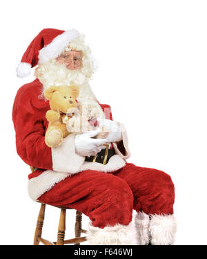 Santa Claus sitting in a chair holding teddy bears for Christmas Stock Photo