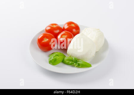 fresh mozzarella, basil and tomatoes - ingredients for caprese salad on white plate Stock Photo