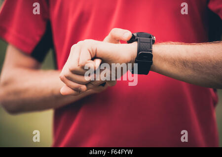 Runner using heart rate monitor training running, smartwatch checking performance or GPS. Man athlete looking at stopwatch. Stock Photo