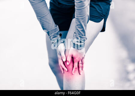 Runners knee leg pain, woman holding sore and overtrained painful knee, sprain or cramp ache filled with red pink bright place.  Stock Photo