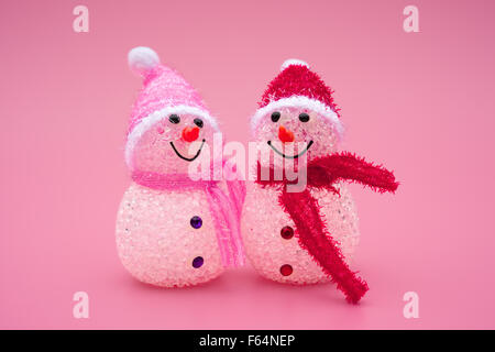 two smiling toy christmas snowman on pink background Stock Photo