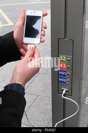 Paris, France. 11th Nov, 2015. A young man charges his smartphone at a USB charging station at a bus stop for local lines RATP in Paris, France, 11 November 2015. With USB connectors and other cables, locals and tourists can charge their electronics around the clock. Photo: FRANZSISKA JAEGER/dpa/Alamy Live News Stock Photo