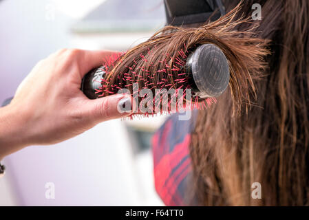 Hairstylist brushing a clients hair with a circular bristle brush Stock Photo