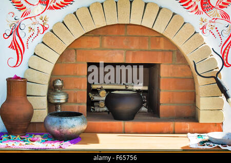 Made of brick layout old stove with firewood inside. Nearby is the old dishes. The layout is beautifully decorated. Stock Photo