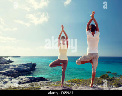 couple making yoga exercises on beach from back Stock Photo