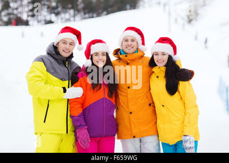 happy friends in santa hats and ski suits outdoors Stock Photo