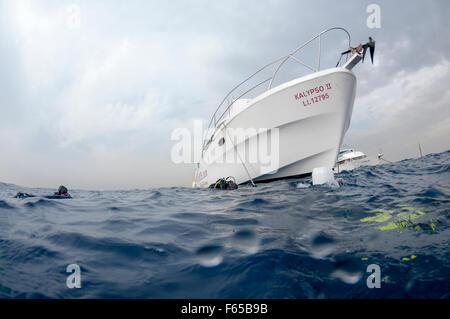 The dive boat is anchored near the dive site and the divers have entered the water Photographed of the coast Larnaca, Cyprus Stock Photo