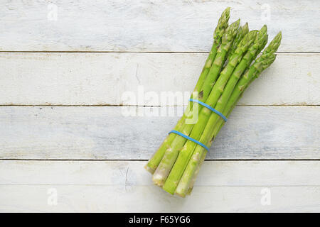 Bunch of fresh asparagus on a white wooden table. Empty copy space for editor's text. Stock Photo