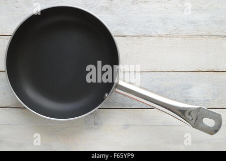 Frying pan on a white wooden table. Top view. Empty copy space for editor's text. Stock Photo