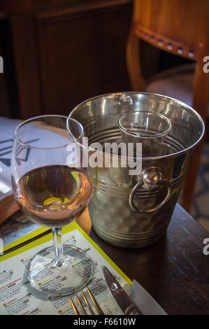 A glass of rosé wine and its carafe in a shiny ice bucket on a restaurant table, Bergues, Nord Pas de Calais, France Stock Photo