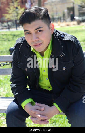 Portrait of a young man wearing a green shirt with a light black jacket looking directly at the camera. Stock Photo